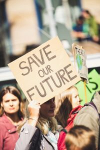 picture of a teenager holding up a protest sign that reads 'save our future'